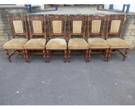 A set of six early 20th Century light oak dining chairs with turned finials, the top rails carved with neo-classical urns abo