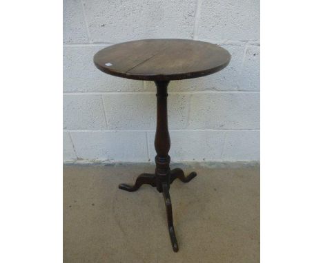 A Georgian oak circular wine table, raised on a turned baluster column to a tripod base.