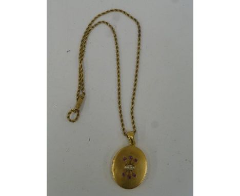 A large gold locket (ummarked / tested). The front panel set with four seed pearls and six rubies.