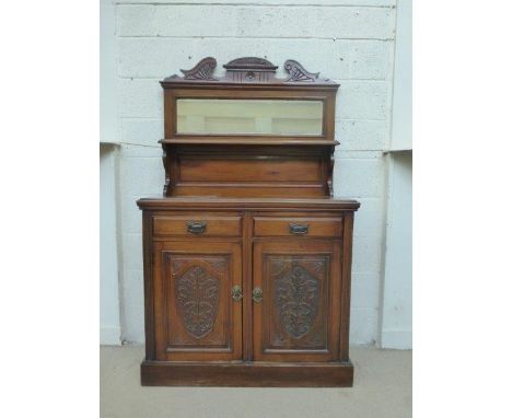 An Edwardian walnut mirror backed chiffonier with a candle shelf above two drawers and a cupboard base with carved decoration