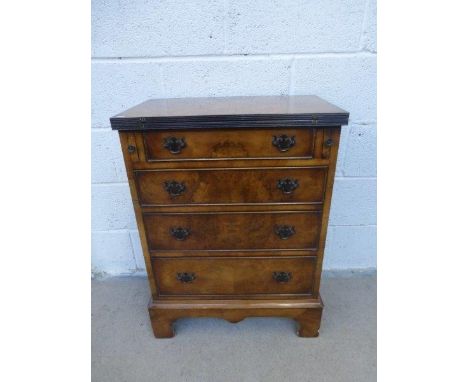 A walnut effect bachelors chest, the fold over top above four graduated drawers, raised on bracket supports.