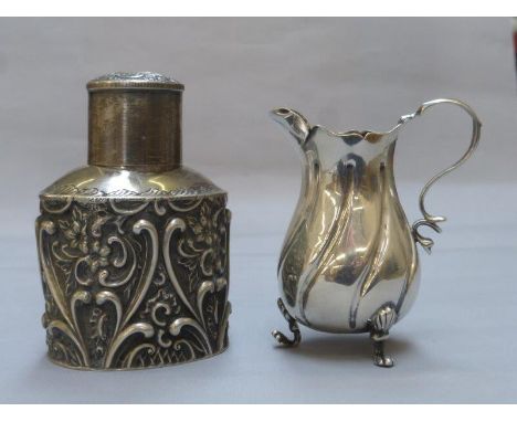 A silver tea caddy with embossed decoration, maker H. Matthews, and a silver cream jug, maker's mark rubbed, Chester 1900.