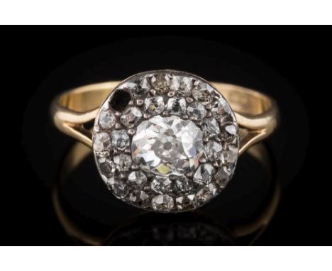 A diamond mounted round cluster ring: with a central oval, old brilliant-cut diamond approximately 0.50ct, pave-set within a 