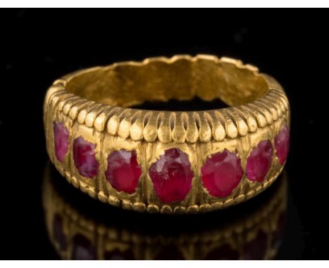 An antique gold and ruby seven-stone ring: with rounded oval rubies in a heavy rub-over setting, approximately 12gms gross we