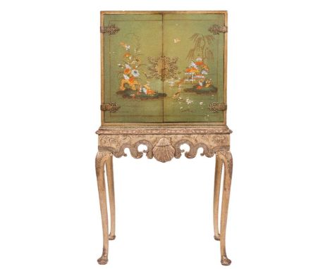 A green lacquer and chinoiserie brass mounted cabinet on carved and silvered wood stand:, the cabinet with a plain interior e