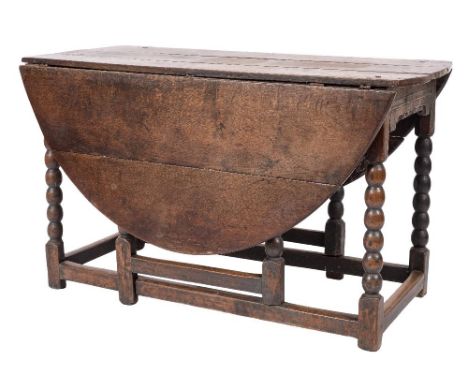 An 18th Century oak gateleg table:, with an oval hinged top and moulded and dentil apron sides, on bobbin turned legs, united