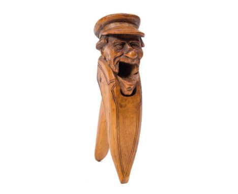 A late 19th century German carved treen nutcracker: depicting a gentleman in a peaked cap with a wart on the end of his nose,