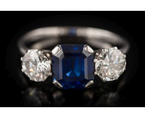 A sapphire and diamond three-stone ring: the rectangular-cut sapphire approximately 7.1mm long x 6.3mm wide x 4.3mm deep in f