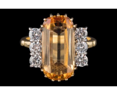 An imperial topaz and diamond cluster ring: with central oblong topaz approximately 17mm long x 8.5mm wide x 5mm deep, estima