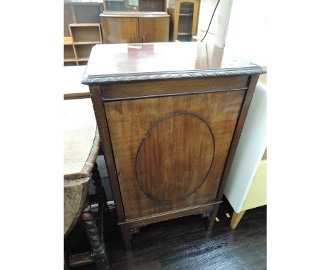 An Edwardian mahogany music cabinet having gadrooned rim with oval applique door and shelf interior on square legs