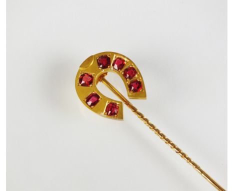 A horse shoe stick pin, set with seven graduated mixed cut red stones, not stamped, weight approx 8.2g