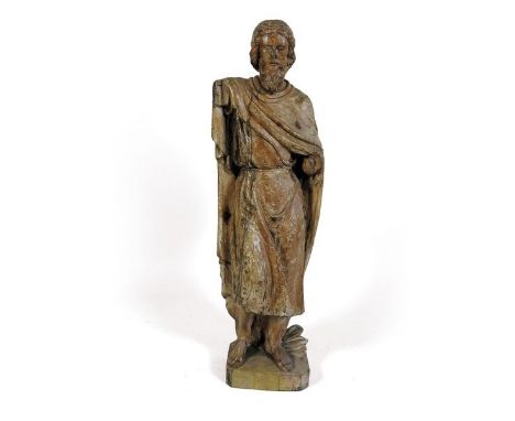 A carved pine figure of a saint, probably North European, 18th century. The figure in a cloak standing on a canted square pli