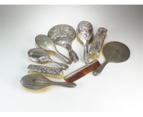 A harlequin collection of silver mounted dressing table wares, comprising; two hand mirrors, four hair brushes, two clothes b