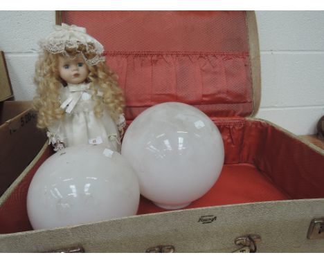 A vintage suitcase, glass globe lampshades, and modern collector's doll