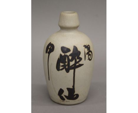 A Japanese sake bottle decorated with hand painted calligraphy. 16.5 cm high.