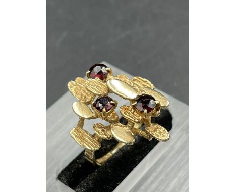 A vintage abstract ring, designed as three round cut garnets, weighing an estimated 0.28, 0.24 and 0.29ct surrounded by polis