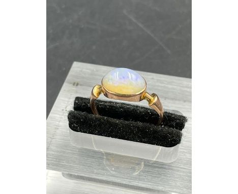 An antique single stone opal ring, oval cabochon cut white opal with a blue green play of colour, weighing an estimated 1.90c