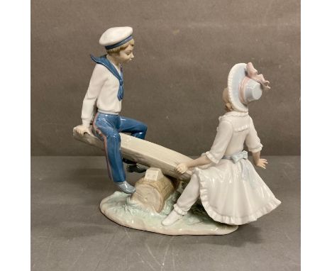 Seesaw. A boy and girl playing on a seesaw. Lladro. Designed by Vincente Martines. #1255. Marked “Lladro Daisa 1977”on base. 