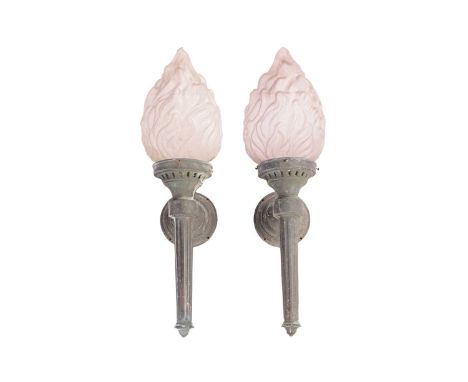 A pair of large architectural green-patinated bronze wall lights in the form of burning torches with opaline flambeau diffuse