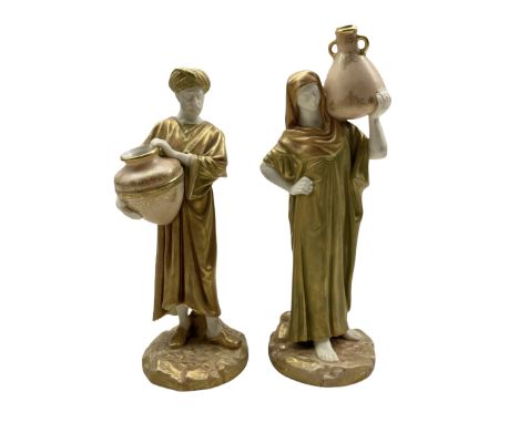 Pair of Royal Worcester porcelain figures modelled as male and female water carriers, dressed in green-gilt robes standing on