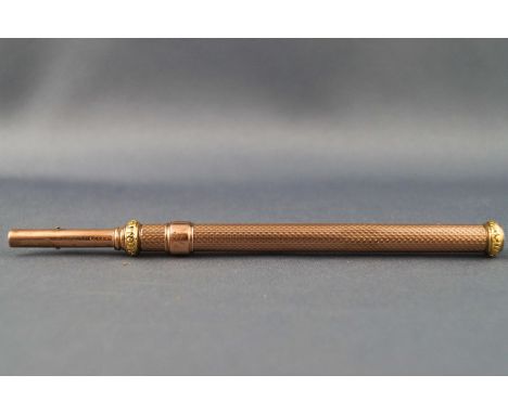 A rose and yellow coloured metal dual action propelling pencil and dip pen with engine turned decoration, stamped J.Bramah Pa