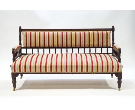 An Edwardian mahogany spindle back sofa with reed and floral striped upholstery