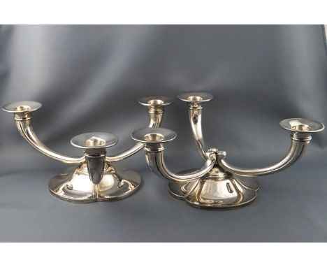 A pair of white metal three branch candelabra with scroll arms on a trefoil floral base, stamped R Ruys 800, (the firm of Ruy