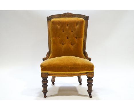 A Victorian nursing chair with carved mahogany show frame, to the yellow button back on turned legs