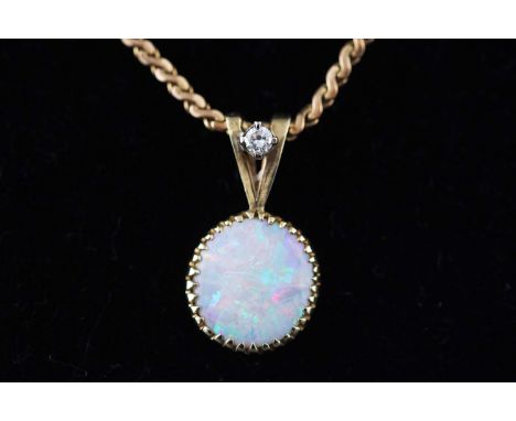 A handmade yellow metal pendant set with a shallow cabochon opal and a single diamond. Suspended from an S link chain with bo