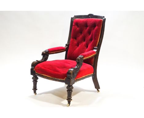 A Victorian armchair with mahogany show frame to the button back, the arms carved with lion heads