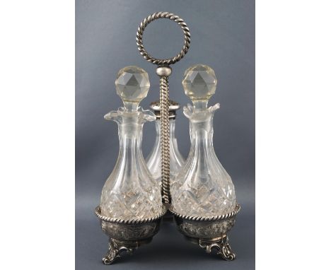 A silver trefoil cruet frame on three feet, suspended from a twisted rope work ringed finial handle, set with three cut glass