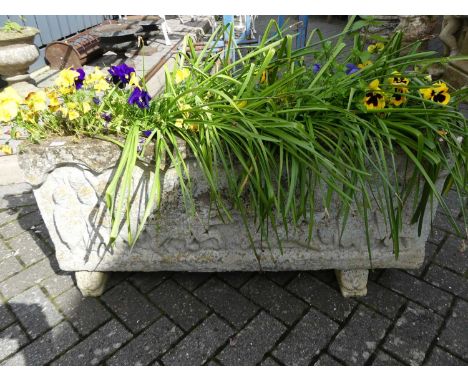 A large reconstituted stone rectangular garden trough planter, raised on squat end feet, the front elevation decorated with r