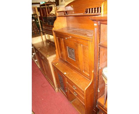 An Arts &amp; Crafts oak students bureau, having integral upper shelf, the fall-front panel enclosing pigeon-hole interior an