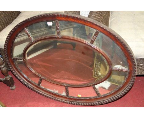 An Edwardian mahogany oval bevelled wall mirror, with gadrooned edge and marginal outer plates, 77.5 x 105cm 
