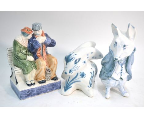Thee Rye Pottery figures - Old couple seated on a bench raised on a rectangular pedestal, 21 cm high to/w a model of a floral