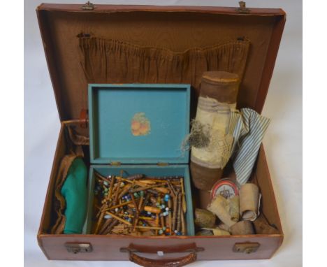 A vintage suitcase containing numerous lace-making bobbins, cylinder with part-made length of lace, several lace templates pr