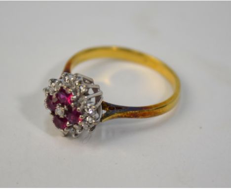 A ruby and diamond cluster ring, the four claw set rubies surrounding a central brilliant cut diamond, with seventeen diamond
