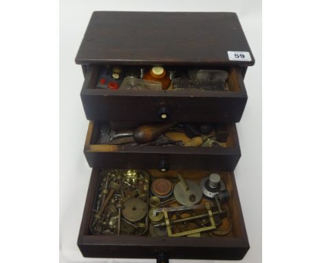 A small chest fitted with three drawers containing assorted watch parts, small tools, clamps etc.