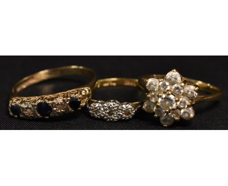 A diamond and 18ct gold trilogy ring; a 9ct gold flower head cluster; a diamond and sapphire ring (3)