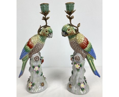 A pair of ceramic candlesticks modelled as parrots sitting atop a stump. With flower and insect applied detail. Each holding 