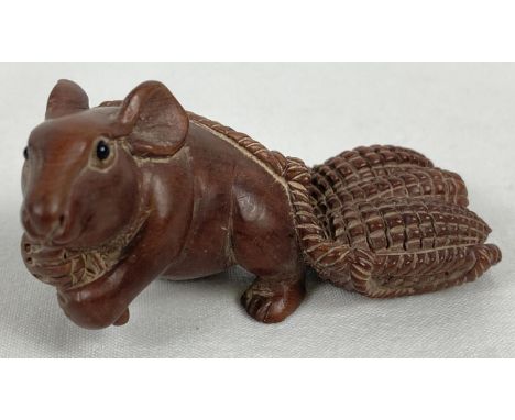 A carved wooden netsuke modelled as a mouse pulling a basket of ears of corn. Set with small mother of pearl disc to undersid