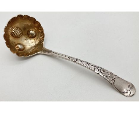 A George III silver sauce ladle with engraved handle of scroll and foliate design. Gilt lined bowl with scalloped rim and fea