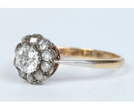 An Edwardian 18 carat gold diamond cluster ring. Set with an old European cut stone approximately 0.65ct with a rose diamond 