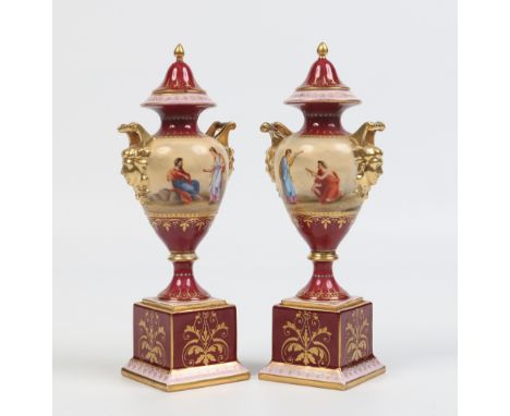 A pair of late nineteenth century Vienna mantel urns. With twin mask handles, claret ground and painted with Classical subjec