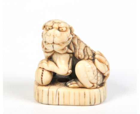 An eighteenth century Japanese carved ivory netsuke formed as a seated Kirin and raised on an ovoid plinth with incised carvi