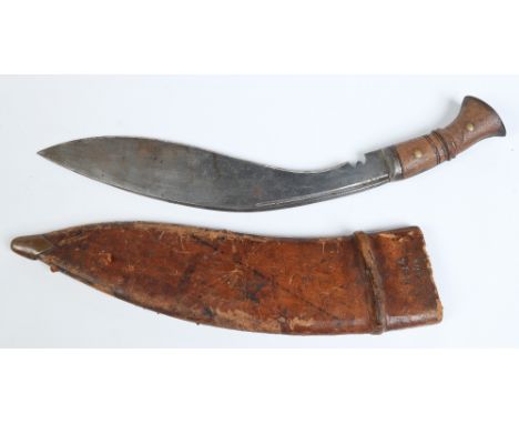A Guerka Kukri knife in leather sheath and with carved hardwood grip. Blade length 34cm. Condition Report. To be used as a gu