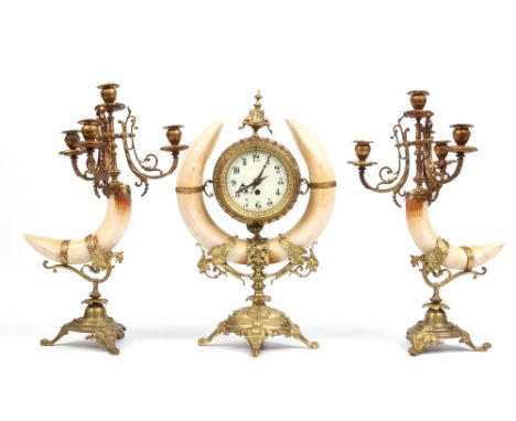 An early twentieth century French gilt brass and warthog tusk clock garniture. With flanking four branch candelabrum and all 