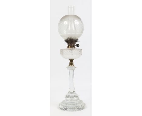 A Victorian oil lamp with frosted shade, cut glass font and raised on an octagonal glass plinth over a stepped circular foot,