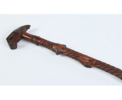 An early nineteenth century wooden walking stick. The handle carved in the form of a hand and with twist sections carved to t