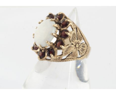 A contemporary 9ct gold opal and garnet dress ring, the claw set opal surrounded by round cut garnets, with flower head pierc